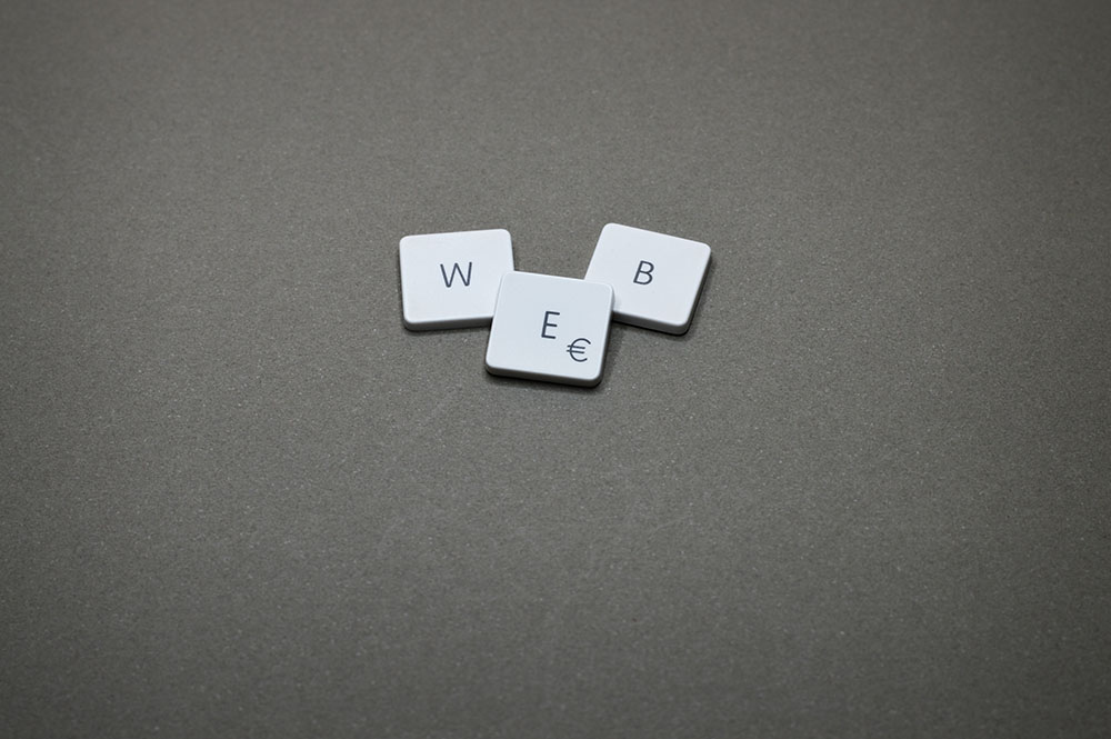 scrabble letter on gray cloth, spelling the word WEB